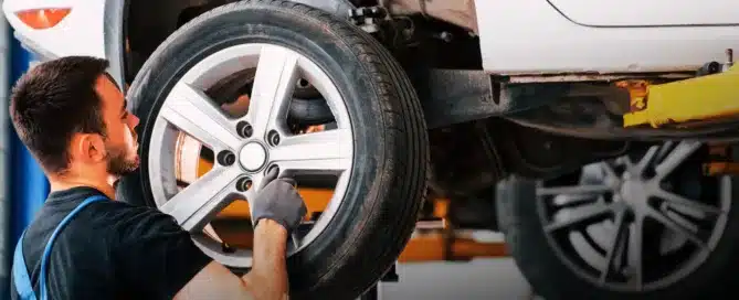 Mechanic servicing a vehicle's brakes and checking AC and electrical systems in a professional garage.