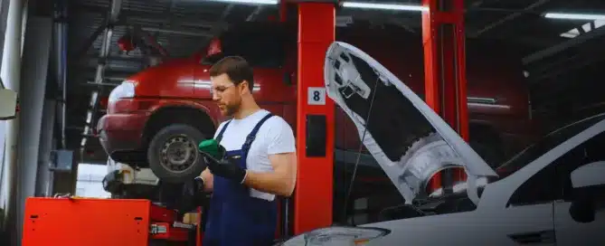 Top-rated mechanic at Carage Auto inspecting a car engine inside a clean, professional auto repair shop.