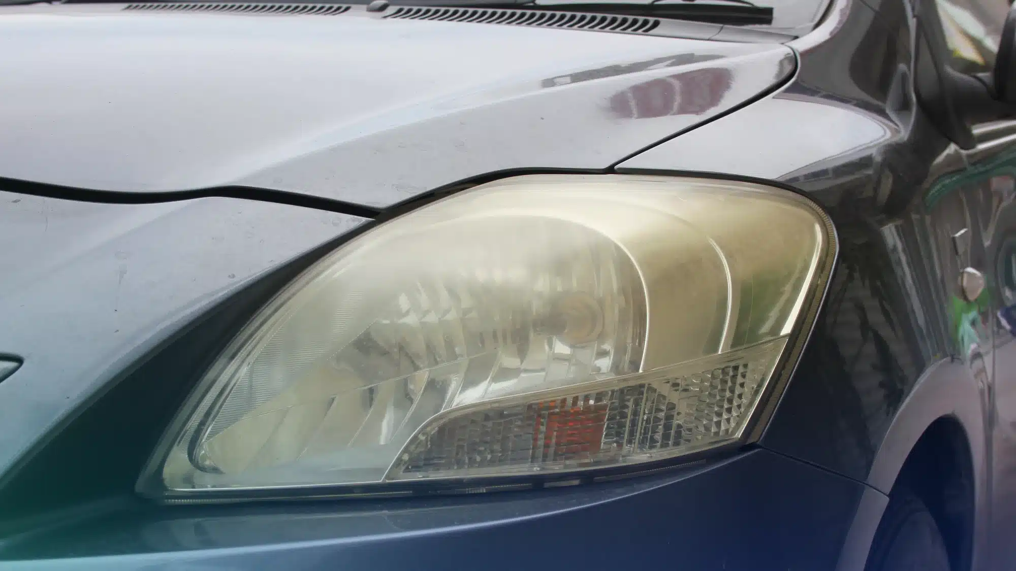 Auto technician restoring cloudy headlights using polishing and cleaning process to improve visibility and vehicle appearance