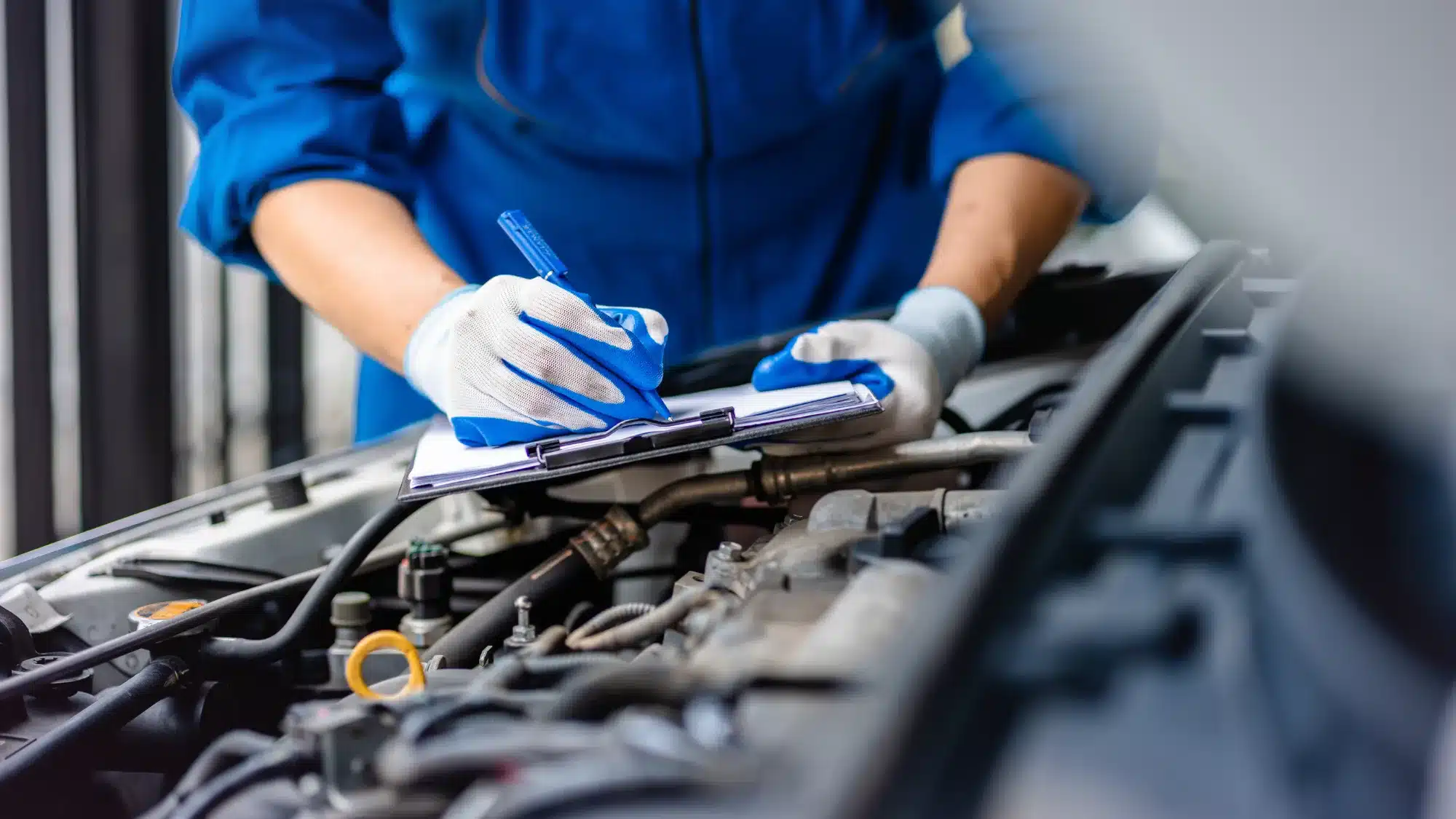 Auto technician performing engine inspection and maintenance service in a professional auto repair shop