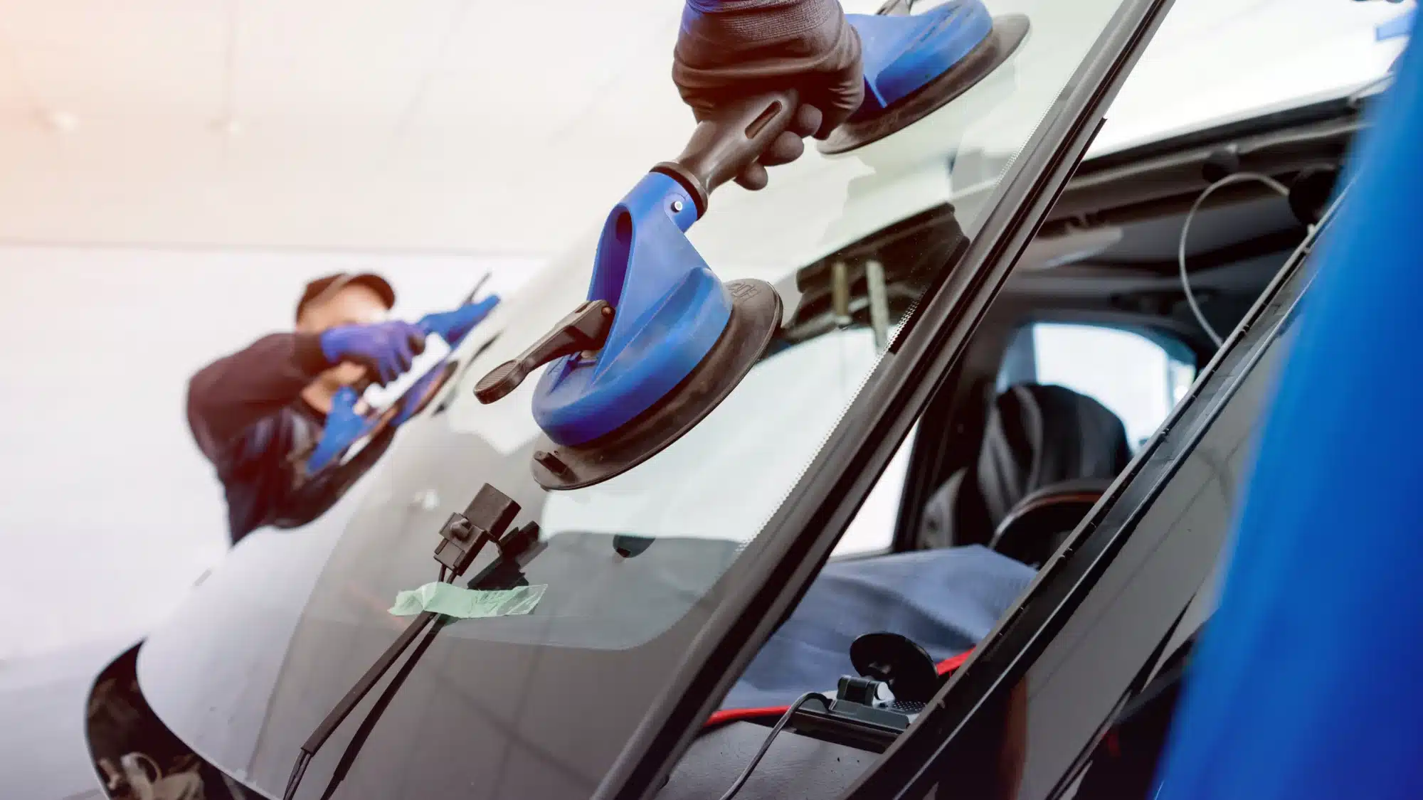 Auto technician repairing a cracked windshield while explaining cost factors for windshield repair in Jupiter Florida