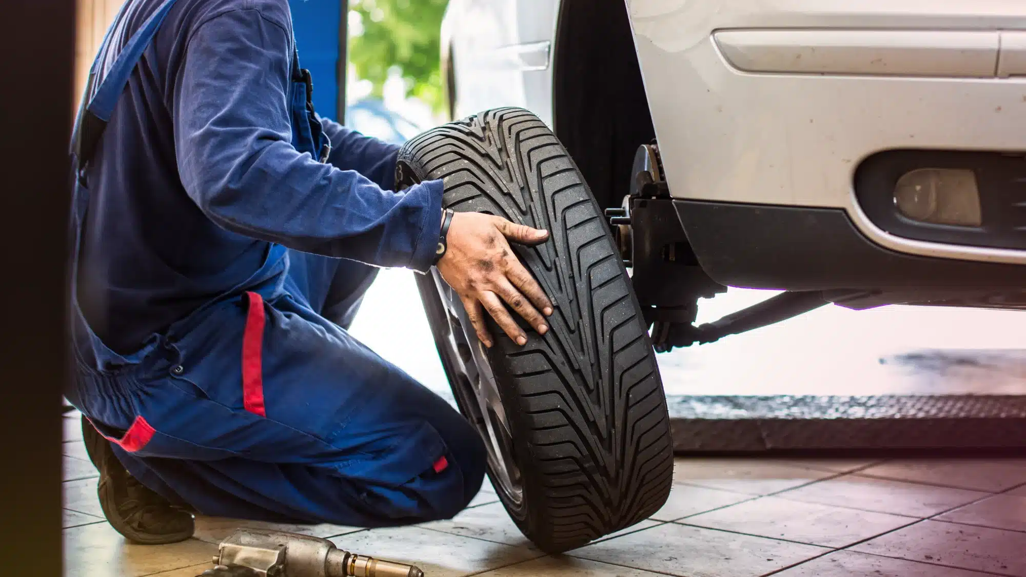 Auto technician performing tire rotation and inspection to ensure vehicle safety and extend tire lifespan