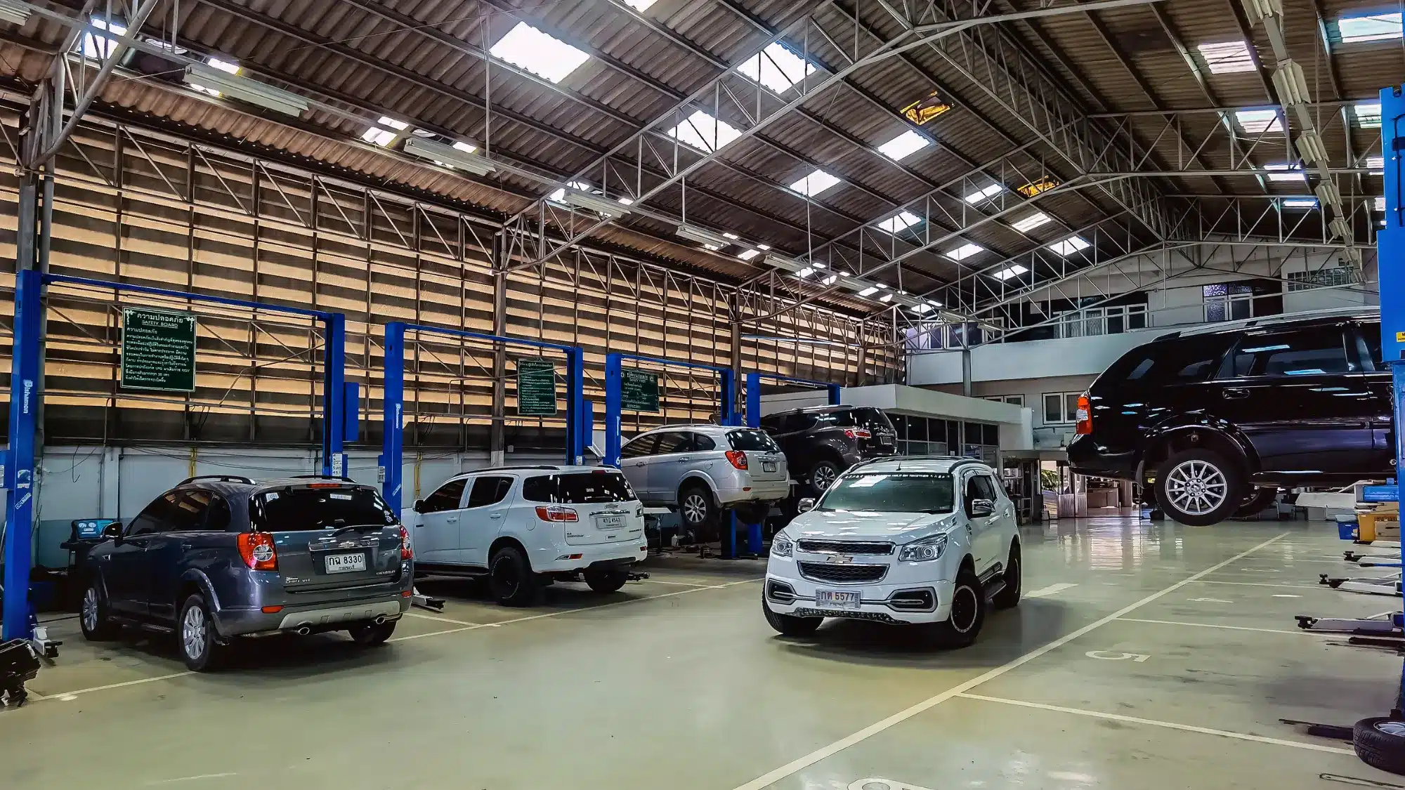 Professional mechanic performing a routine check on a Chevrolet sedan in a clean, well-equipped service bay.
