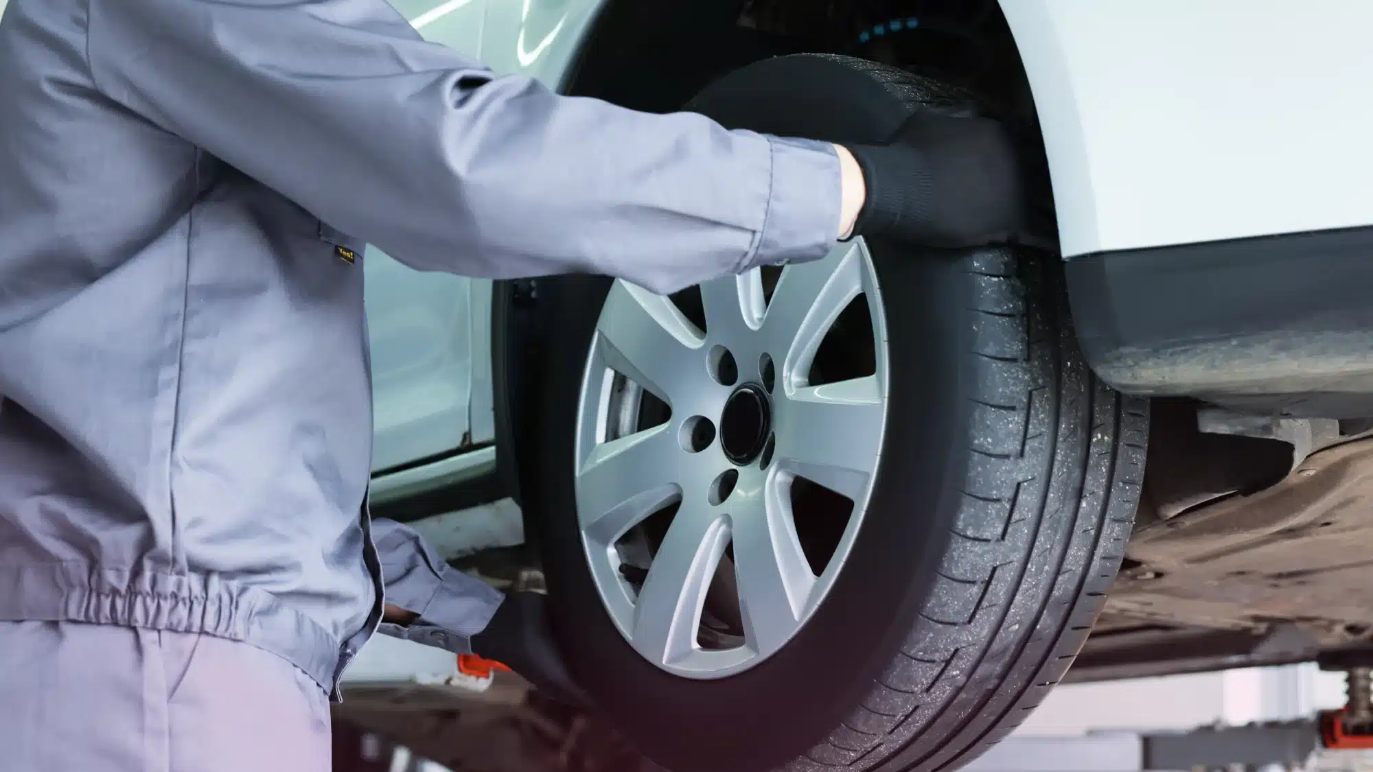 Driver smiling, car tires freshly serviced at a trusted, local automotive repair shop.