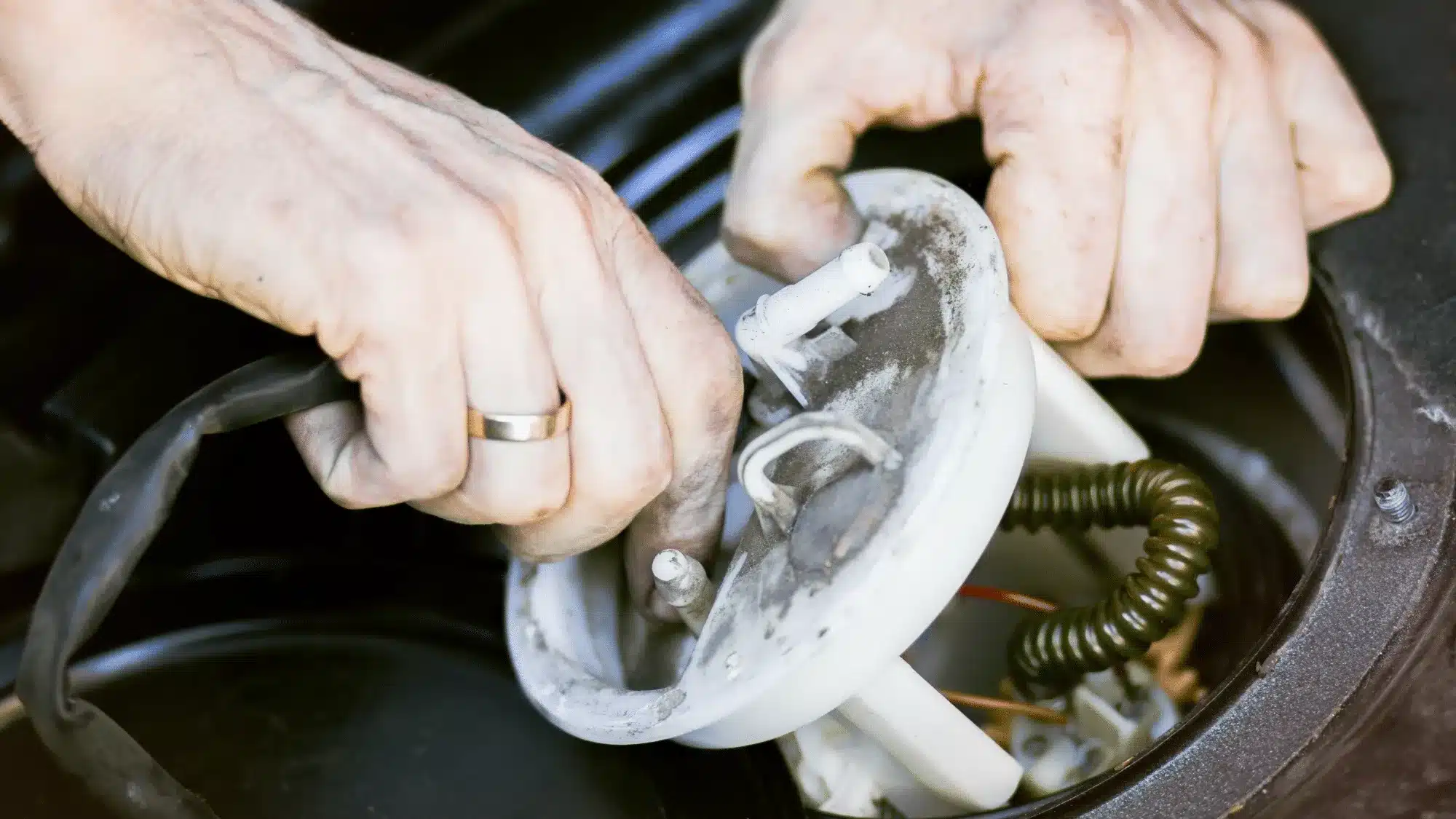 Mechanic inspecting a car's fuel pump at a repair shop in Jupiter, FL.