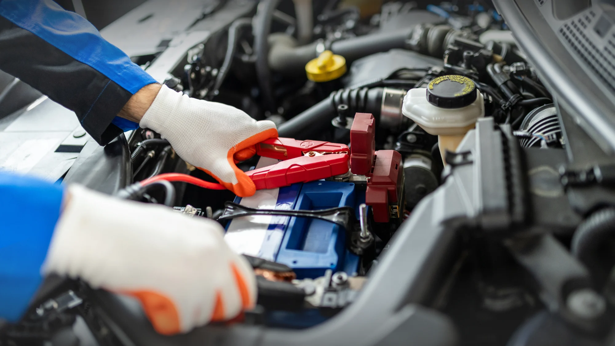 Carage auto repair technician checking a car battery to diagnose electrical and engine-related problems